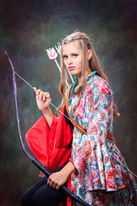 Portrait of young woman holding archery bow