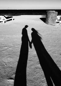 High angle view of couple shadow on sand at beach