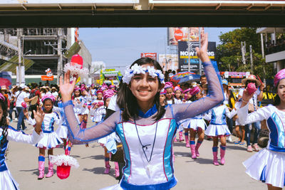 Happy young woman with arms raised in city