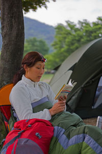 Woman reading a book at campsite