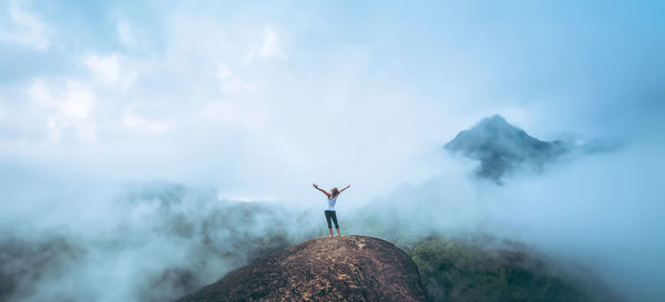 Rear view of man standing on mountain against sky