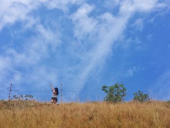 Woman standing on field against sky