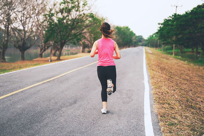 Rear view of woman running on road