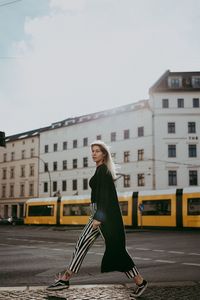 Full length of young woman in city against sky