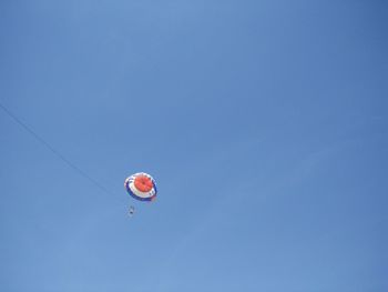 Low angle view of person parasailing against blue sky