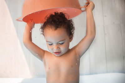 Happy kid playing in an inflatable pool in backyard. curly toddler smiling and playing with water