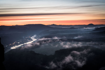 Scenic view of mountains against dramatic sky during sunset