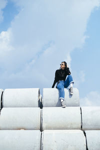 Low angle view of woman sitting against sky