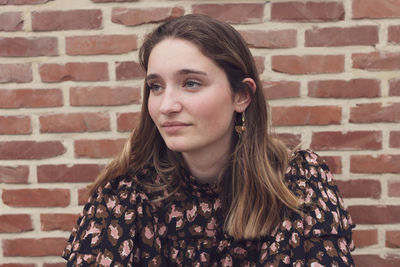 Portrait of young woman against brick wall