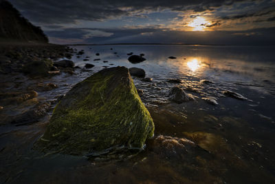 Scenic view of rocks in sea during sunset