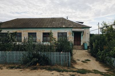 Old house by building against sky