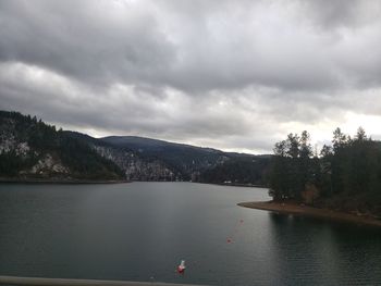 Scenic view of lake by trees against sky