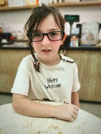 Portrait of girl wearing eyeglasses leaning on a table