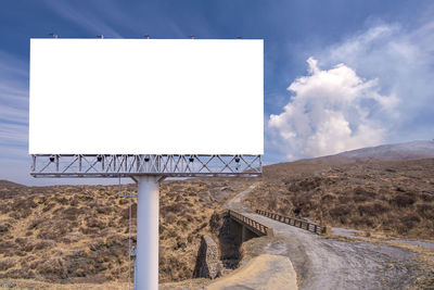 Road sign on landscape against sky