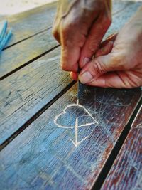 Cropped hands of person making heart shape on wooden table