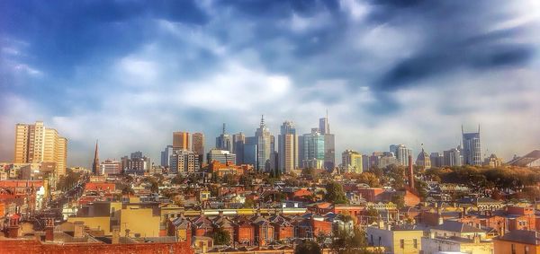 Skyscrapers in city against cloudy sky