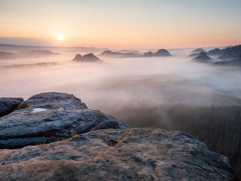 Scenic view of rocks in mountains against sky during sunset