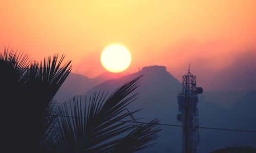 Silhouette electricity pylon against sky during sunset