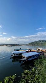 Boats moored in lake against sky