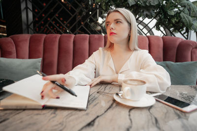 Midsection of woman with coffee cup on table