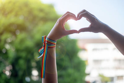 Low angle view of hands creating heart shape outdoors