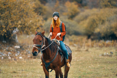 Close-up of young woman riding horse on land