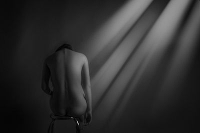 Rear view of shirtless woman against black background