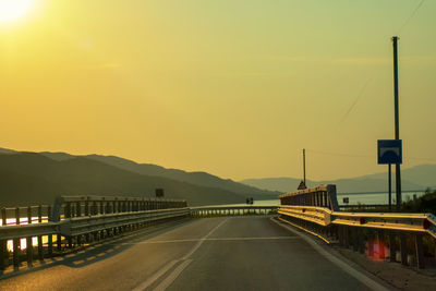 Road by bridge against sky during sunset