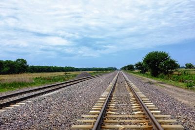 Railroad tracks passing through landscape against sky
