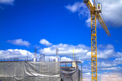 Low angle view of cranes against blue sky