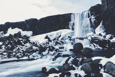 Waterfall over rock formation during winter