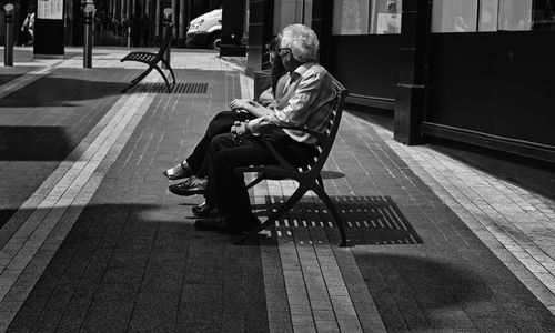 Man sitting on bench in city
