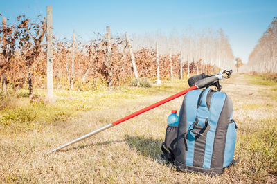 Backpack with hiking poles on field against sky