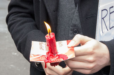 Midsection of person holding lit candle