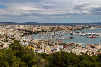 Aerial view of city by sea against sky