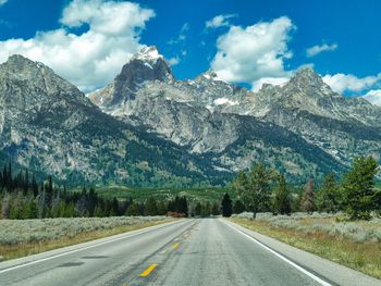 Road by mountains against sky