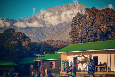 People by buildings against mountain range