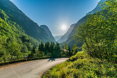 Road amidst trees and mountains against sky