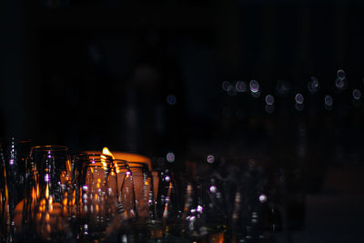 Close-up of glasses and candle on display at night