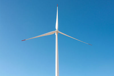 Low angle view of windmill against clear blue sky