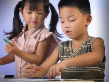 Close-up of boy with sister holding crayon