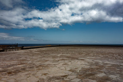 View of calm beach against cloudy sky