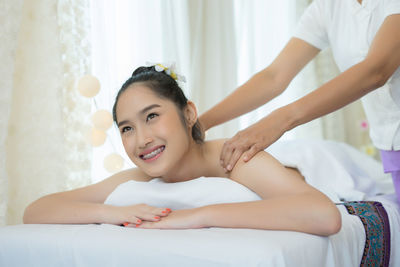 Smiling young woman receiving massage in spa