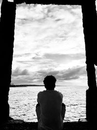 Rear view of man looking at sea against sky