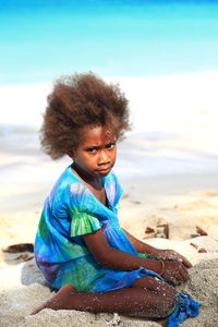 Portrait of woman sitting on shore at beach against sky