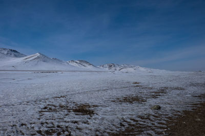 Scenic view of frozen lake against blue sky