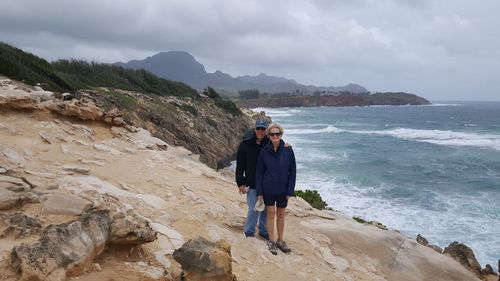 Portrait of couple standing at beach against sky