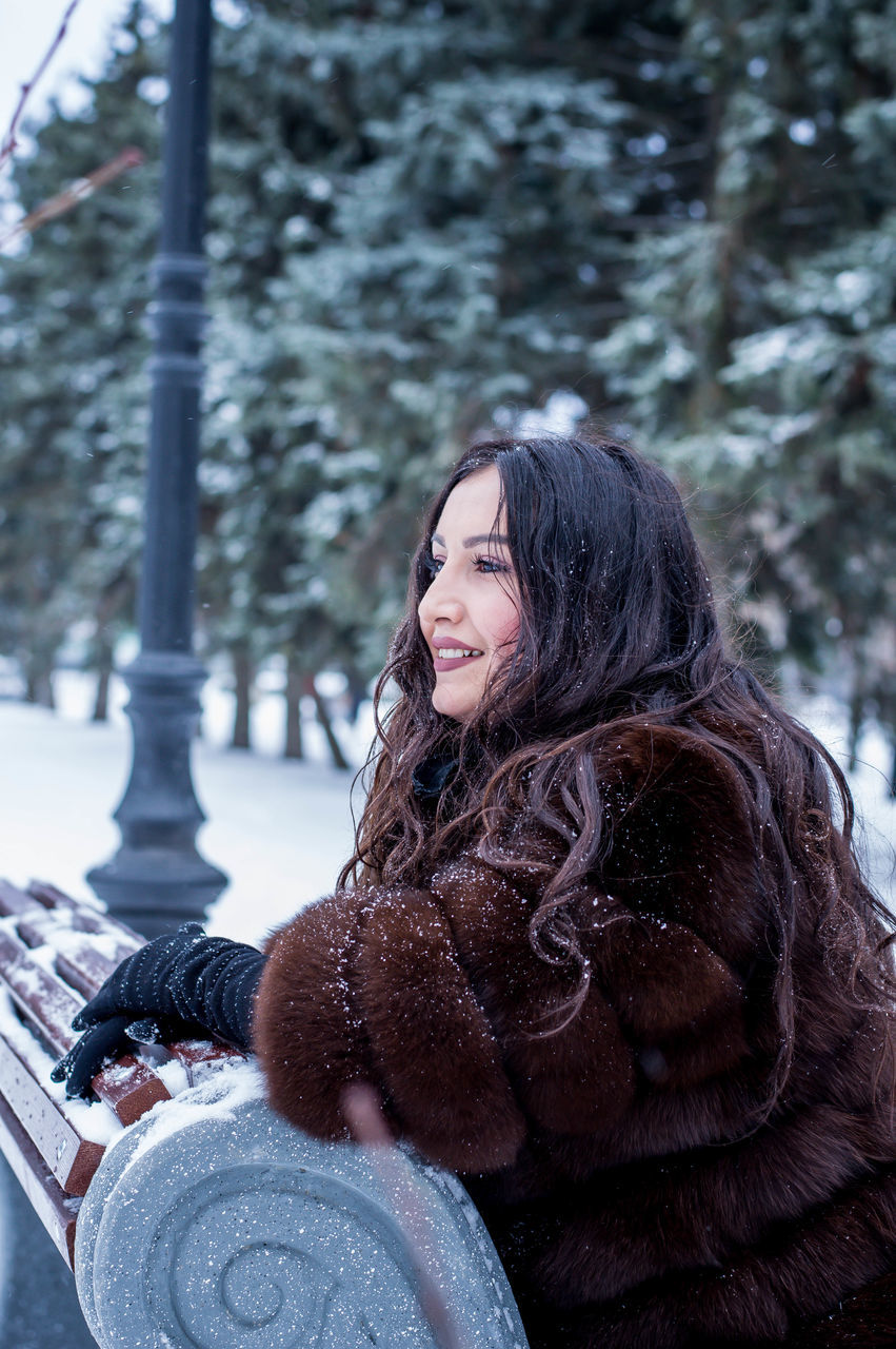 winter, snow, lifestyles, young women, one person, warm clothing, leisure activity, young adult, cold temperature, smiling, real people, outdoors, happiness, day, beautiful woman, tree, nature, snowing, people