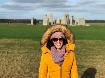 Smiling young woman standing against stonehenge