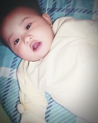 Close-up portrait of baby lying on bed